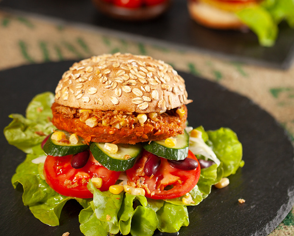 KI generiert: Ein veganer Burger mit Haferbrötchen, Salat, Tomate, Gurke und Kidneybohnen.
