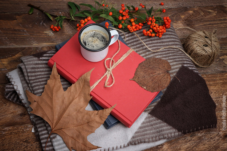 Herbststimmung mit Blättern, warmem Getränk und Büchern