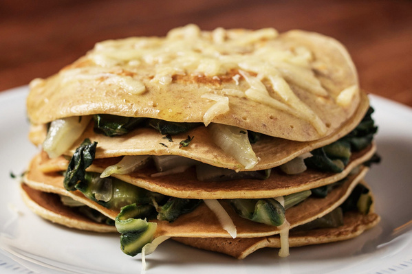 KI generiert: Ein Stapel Pfannkuchen, gefüllt mit Spinat und Käse, auf einem Teller.