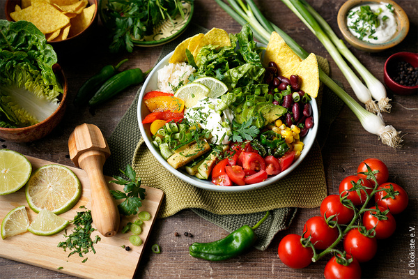 Burrito Bowl in Schüssel mit Zutaten auf Holzfläche