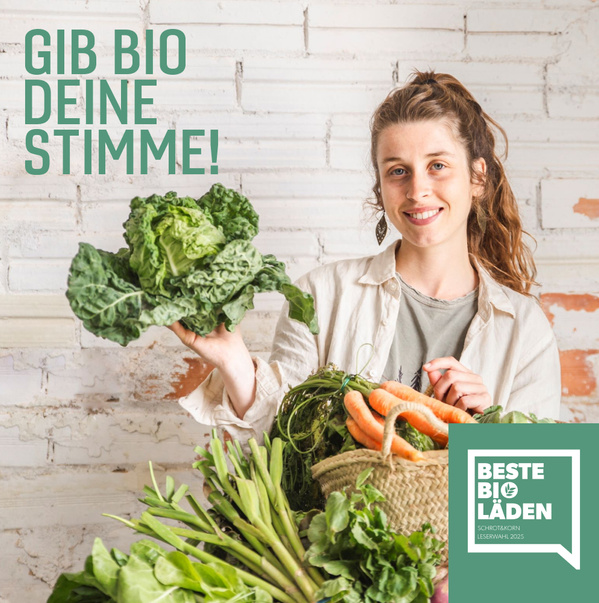 KI generiert: Eine Frau hält frisches Gemüse in den Händen und lächelt, während sie vor einer hellen Backsteinwand steht. Auf dem Bild steht der Slogan "Gib Bio Deine Stimme!" und es gibt ein Logo von "Beste Bio Läden 2025".