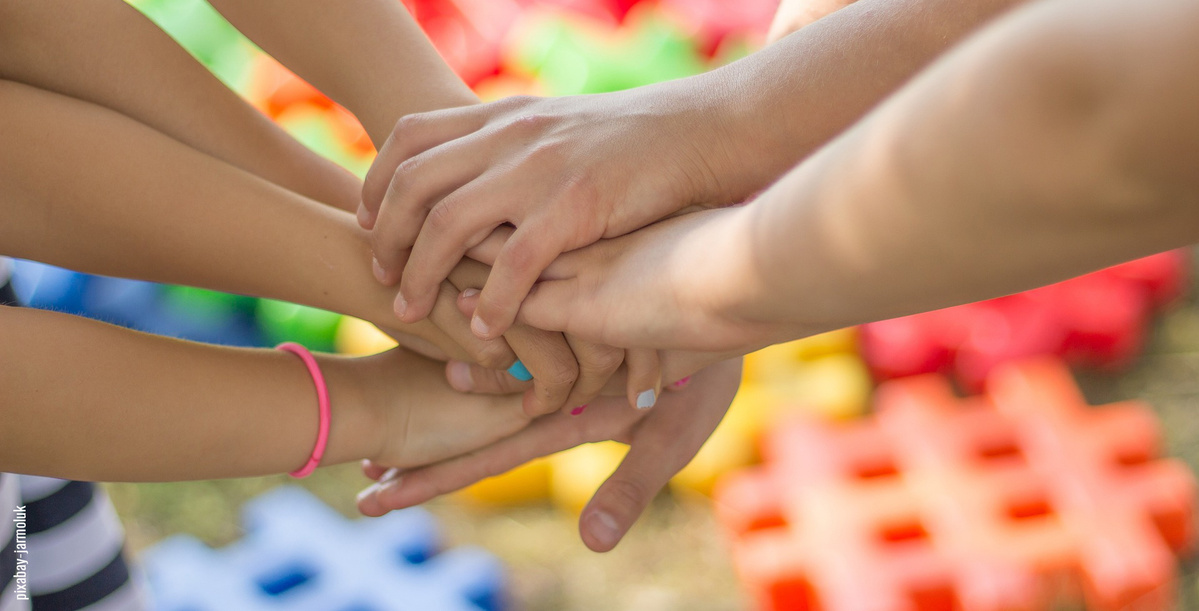 Mehrere Hände übereinander zum Zeichen des Zusammenhalts