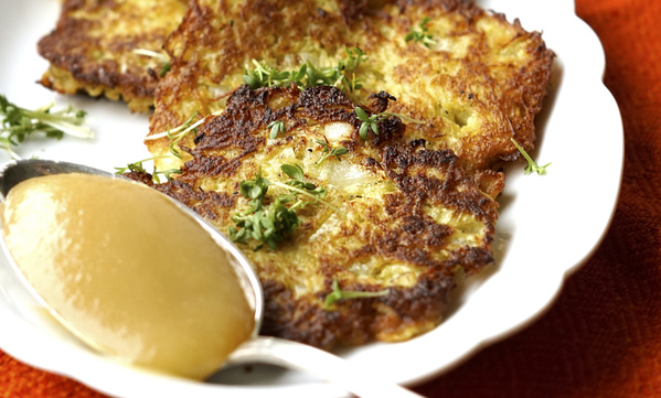 KI generiert: Knusprige Reibekuchen mit frischen Kräutern und Apfelmus auf einem Teller.