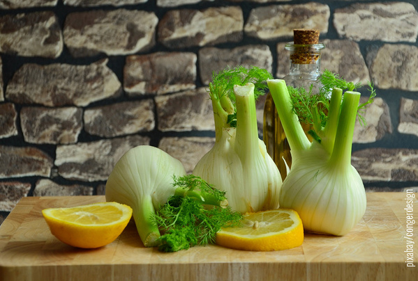 Fenchel und Zitronennscheiben auf Holzbrett vor Wand