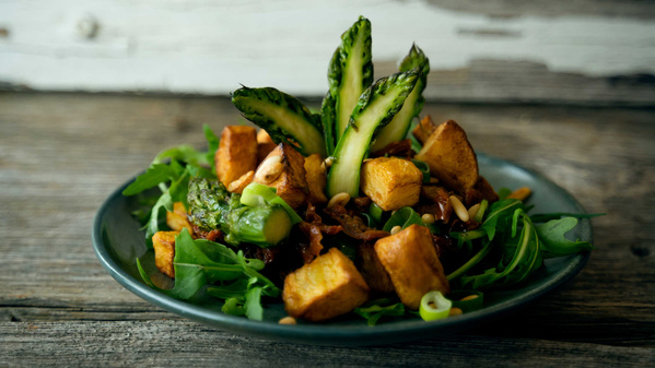 KI generiert: Ein Teller mit grünem Spargel, gebratenen Kartoffeln, Rucola und Nüssen.