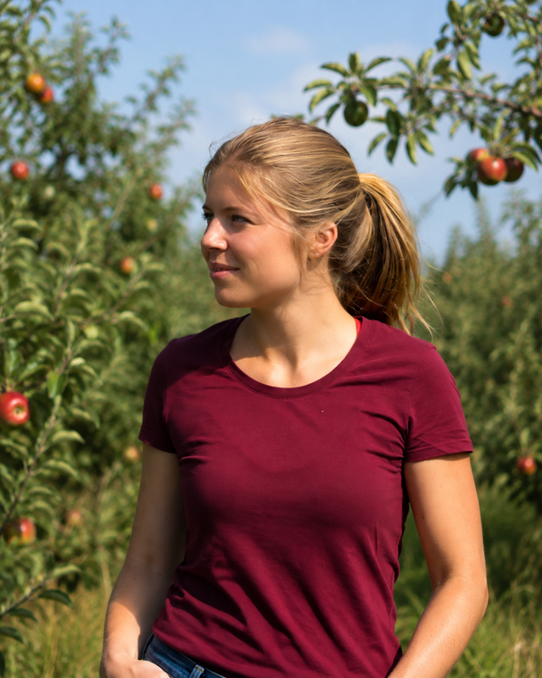 Anna Cordes steht in einem Obstgarten voller reifer Äpfel.