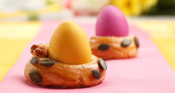 KI generiert: Dekorative, gefärbte Eier in Brezelringen mit Kürbiskernen auf farbigem Tuch.