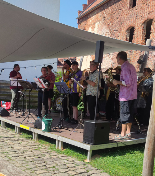 KI generiert: Eine Band spielt auf einer kleinen Bühne im Freien.