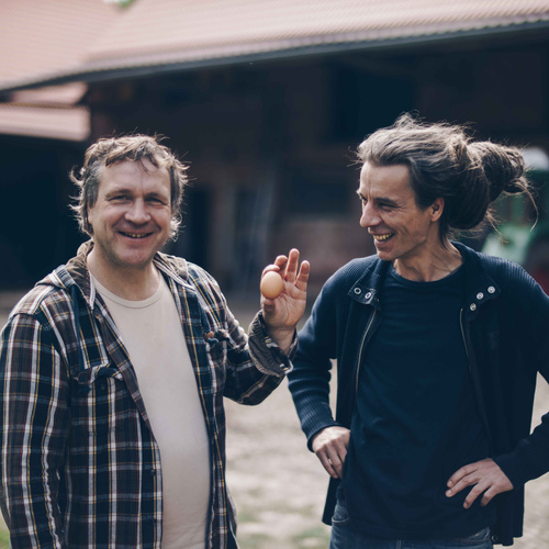 Jens Kulow vom Biolandhof Wiersdorf mit Ei in der Hand und Felix vom Grünland