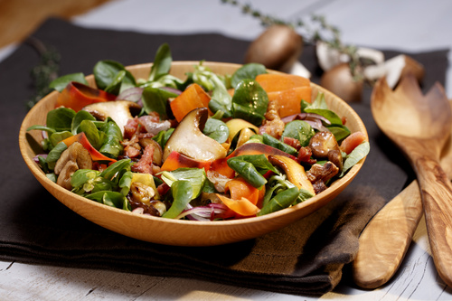 Bunter Salat in Keramikschüssel auf Holzbrett