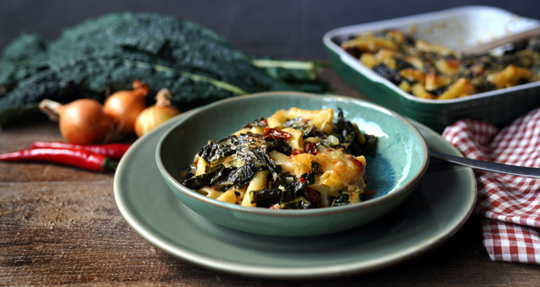 KI generiert: Ein Teller mit einem Gemüseauflauf, umgeben von Zwiebeln, Peperoni und Grünkohl.