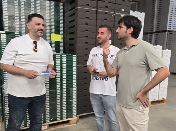 KI generiert: Drei Männer stehen diskutierend vor gestapelten Kisten. Text auf dem T-Shirt: "WHAT PART OF ... UNDERSTAND".