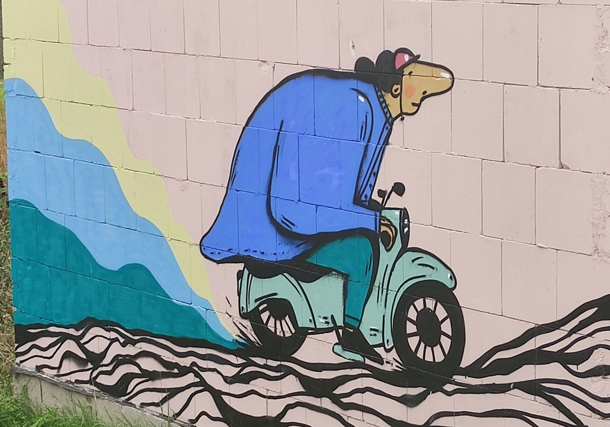 Graffiti auf weißer Mauer: Mann mit Vespa fröhlich unterwegs