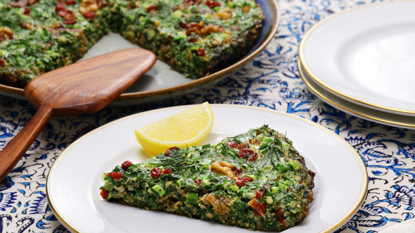 KI generiert: Ein Stück Kräuterfrittata mit einer Zitronenscheibe auf einem Teller.