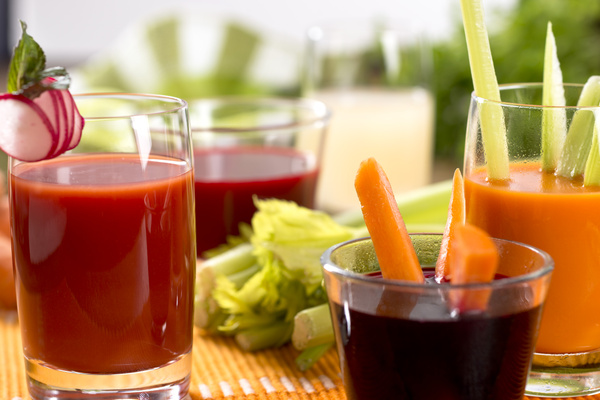 Frische Gemüsesäfte im Glas mit Möhrensticks und Radieschenscheiben garniert