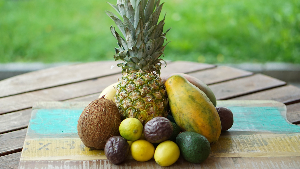 Exotische Obstmischung mit Ananas, Kokosnuss, Papaya auf Holzbrett aus Recyclingsholz
