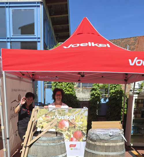 KI generiert: Ein rotes Voelkel-Zelt mit zwei Personen dahinter. Text: "Voelkel".