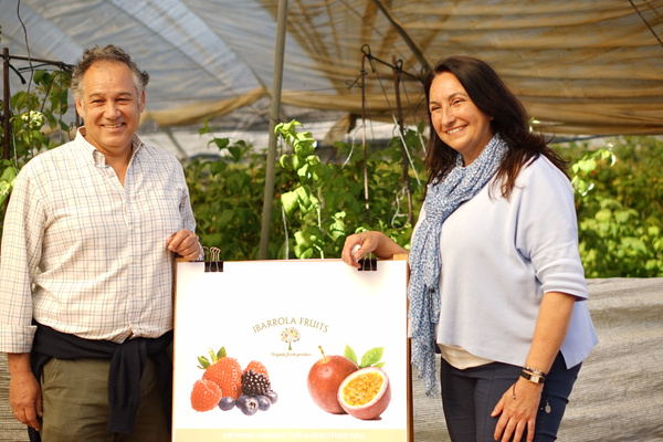KI generiert: Zwei Personen neben einem Schild mit Früchten. Text: "IBARROLA FRUITS... GROWING ORGANIC FOR A HEALTHIER YOU."