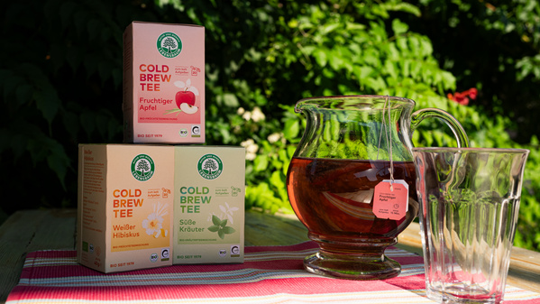 Cold Brew Tee-Verpackungen mit Krug und Glas auf einem Tisch im Freien. 
