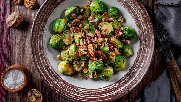 Ein Teller mit lauwarmen Rosenkohl-Salat mit Speck und Nüssen