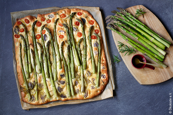 Foccacia mit grünem Spargel und Tomaten auf Holzbrett