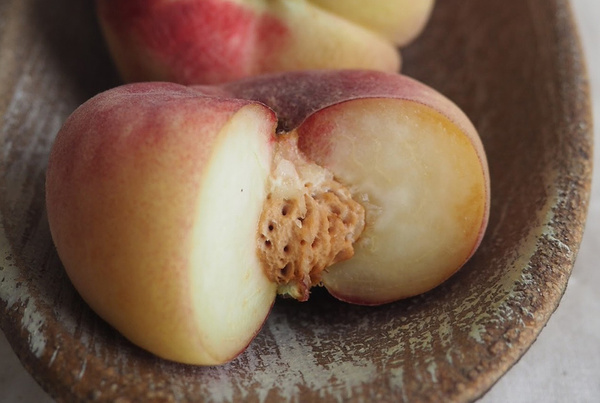 KI generiert: Ein halber Pfirsich mit Kern auf einem rustikalen Teller.