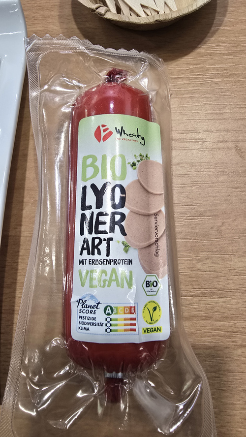 KI generiert: Verpackte vegane Wurst mit Erbsenprotein. Text: "BIO LYONER ART, MIT ERBSENPROTEIN, VEGAN, PLANET SCORE".