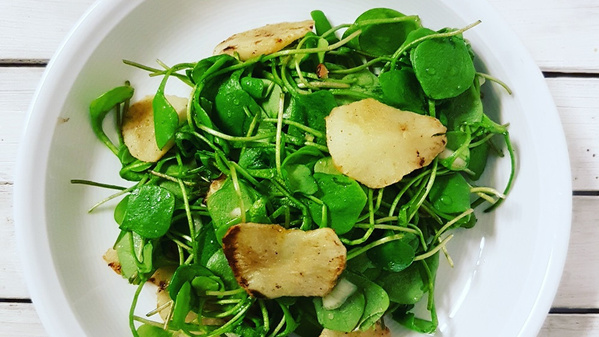 KI generiert: Ein Teller mit einem Salat aus grünen Blättern und gerösteten Knollenscheiben.