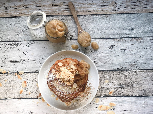 Pancakes mit Birnenkompott und Mandelsplittern auf rustikalem Holztisch.