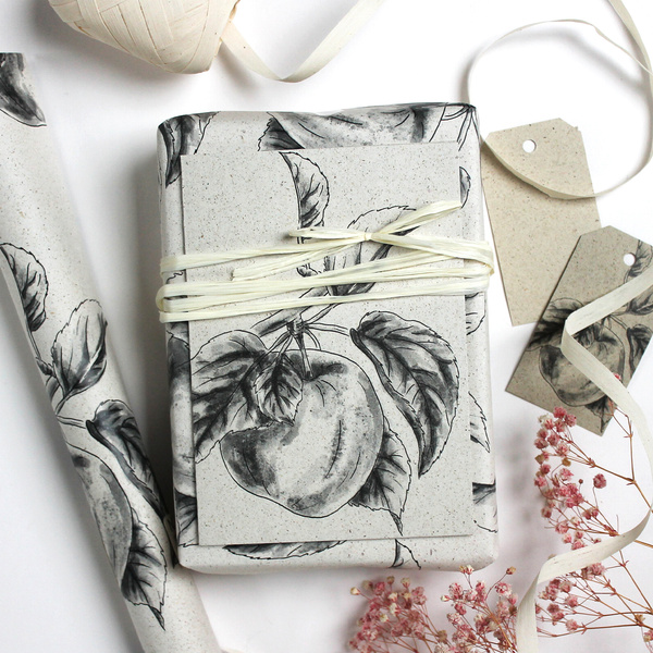 KI generiert: Geschenkverpackung mit Apfeldruck und Raffiaband, umgeben von Geschenkanhängern und Blumen.