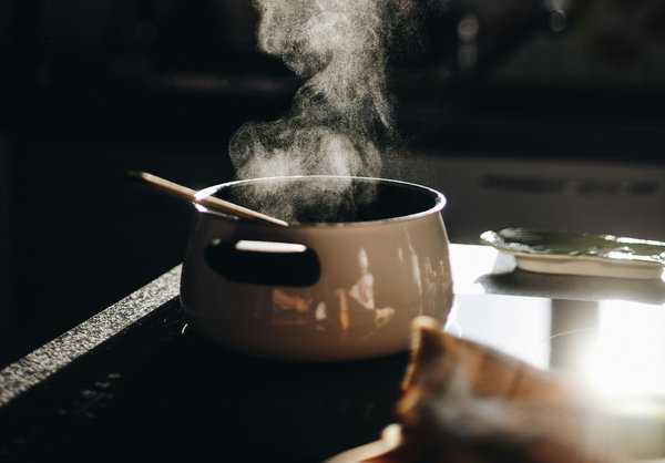 KI generiert: Ein Topf mit Dampf und einem Holzlöffel in einer Küche.