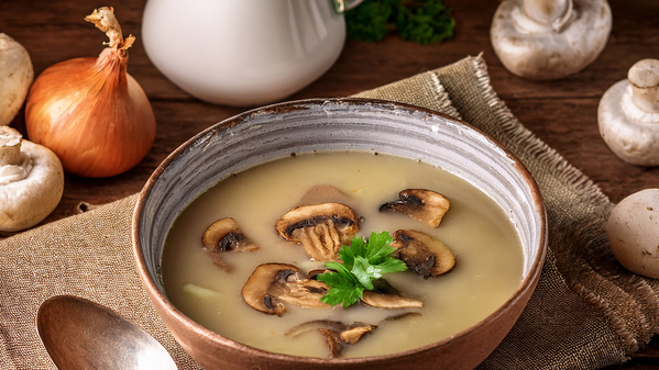Ein Teller mit Champignonsuppe mit Pilzscheiben garniert 