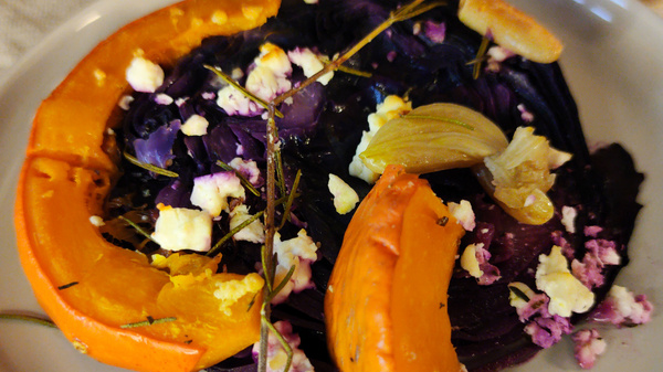 Ein Gericht mit Kürbis, Rotkohl, Feta und Kräutern auf einem Teller.