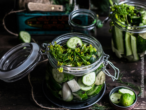 Geöffnetes Bügelglas mit Gürkenscheiben und Dillblüten