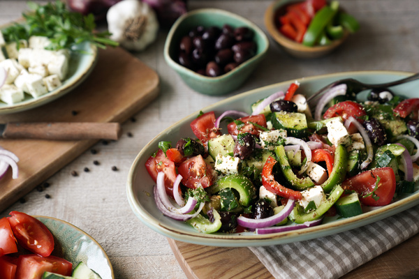 KI generiert: Ein frischer griechischer Salat mit Tomaten, Gurken, Paprika, Zwiebeln, Oliven und Feta in einer Schüssel.