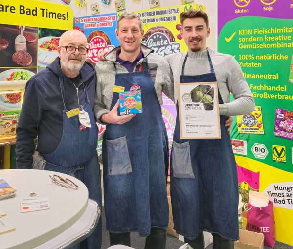 KI generiert: Drei Personen in Schürzen bei einem Messestand. Text: "URKUNDE CERTIFICATE".
