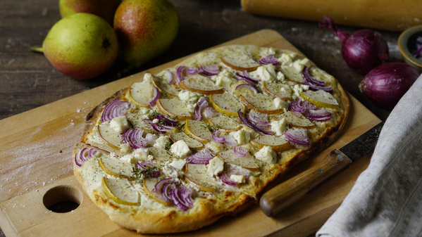 Holzbrett mit Flammkuchen drauf