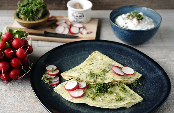 KI generiert: Kräuterpfannkuchen mit Radieschen und Kresse auf einem Teller, neben Salat und frischen Radieschen.