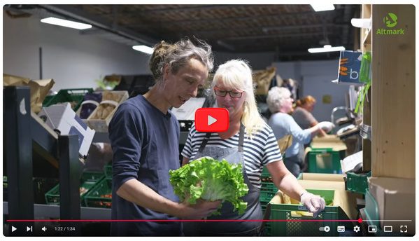 KI generiert: Mehrere Personen sortieren frische Salate in einem Lager. Oben rechts ist das Logo "Altmark" zu sehen.