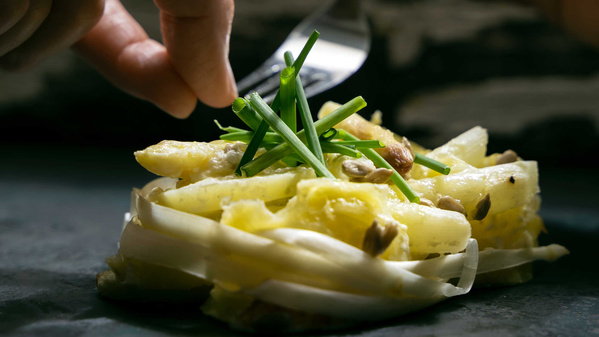 KI generiert: Ein Teller mit verzierten Spargelstücken, garniert mit frischem Schnittlauch.