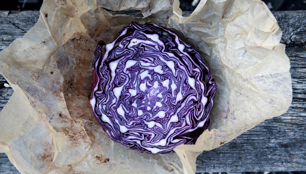 KI generiert: Ein halber Rotkohl liegt auf braunem Papier auf einem Holztisch.