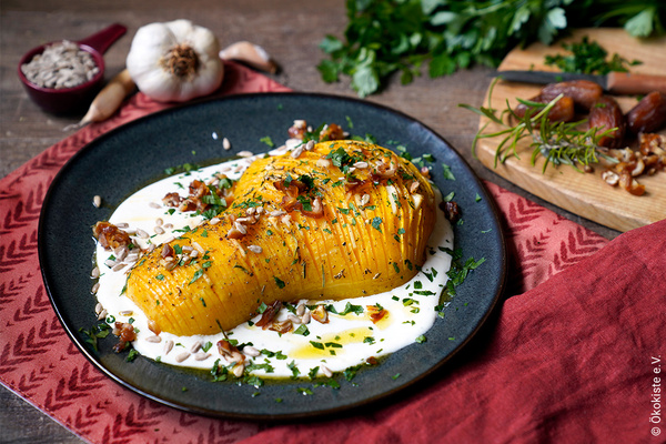 Halber gefächerter Butternut-Kürbis auf Ziegenkäsecreme auf blauem Keramikteller