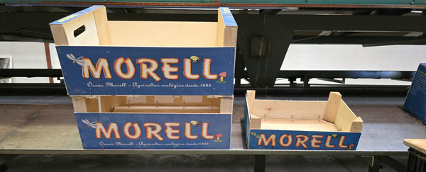 KI generiert: Das Bild zeigt drei Holzboxen mit der Aufschrift "MORELL" in verschiedenen Größen, die auf einer Metalloberfläche stehen. Die Boxen scheinen für die Verpackung oder Lagerung von Produkten gedacht zu sein.