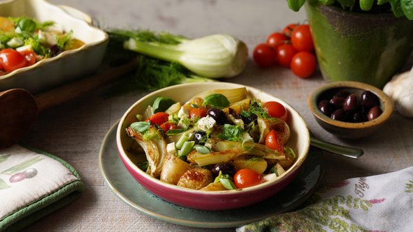 Ein frischer Salat mit Tomaten, Oliven und Fenchel in einer Schüssel, umgeben von frischen Zutaten.
