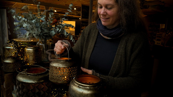 Frau stellt eine Laterne mit einem Teelicht zu anderen Laternen dazu