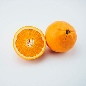 KI generiert: Das Bild zeigt eine ganze Orange und eine halbierte Orange, die nebeneinander auf einer hellen Oberfläche liegen. Der Hauptinhalt des Bildes sind die frischen, saftigen Orangen.