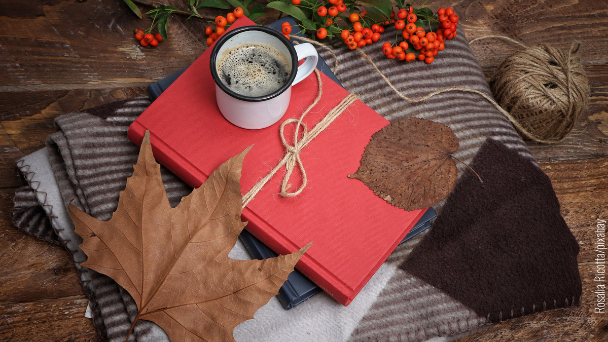 Herbststimmung mit Blättern, warmem Getränk und Büchern