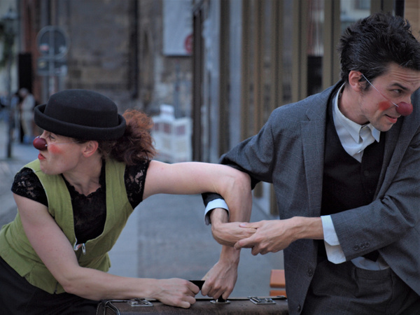 KI generiert: Zwei Pantomimen mit roten Nasen in clownesker Szene auf der Straße.