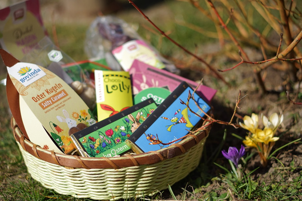KI generiert: Ein Osterkorb mit Süßigkeiten und Blumensamen, umgeben von blühenden Krokussen im Garten.