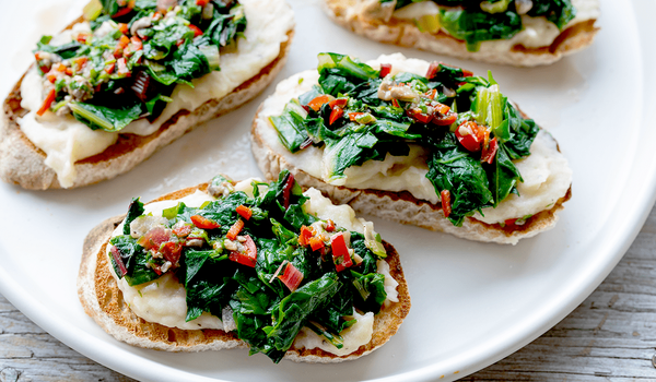 KI generiert: Belegte Brotscheiben mit cremigem Belag und frischem grünem Gemüse auf einem weißen Teller.